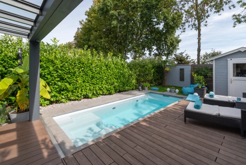 Ein Pool auf einer Holzterasse mit Poolliegen.