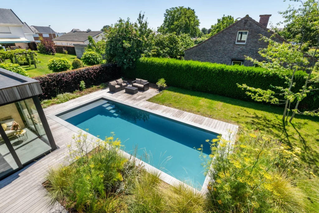 Ein Pool mit Treppe in einem kleinen Garten.